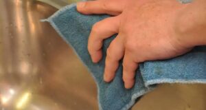 close up of hands cleaning a sink with a rag