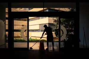 male janitor mopping the entrance with caution: wet floor board sign