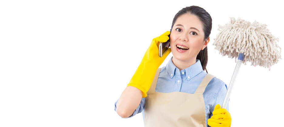 female janitor in uniform holding a mop while talking in the phone