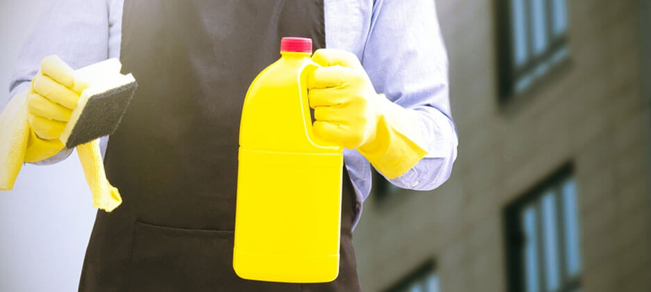 cleaning staff holding a yellow bottle and sponge